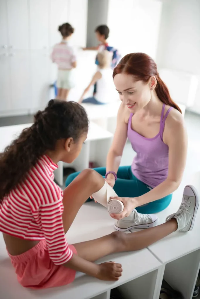 teacher providing first aid to girl with knee ache 2024 10 18 05 22 59 utc